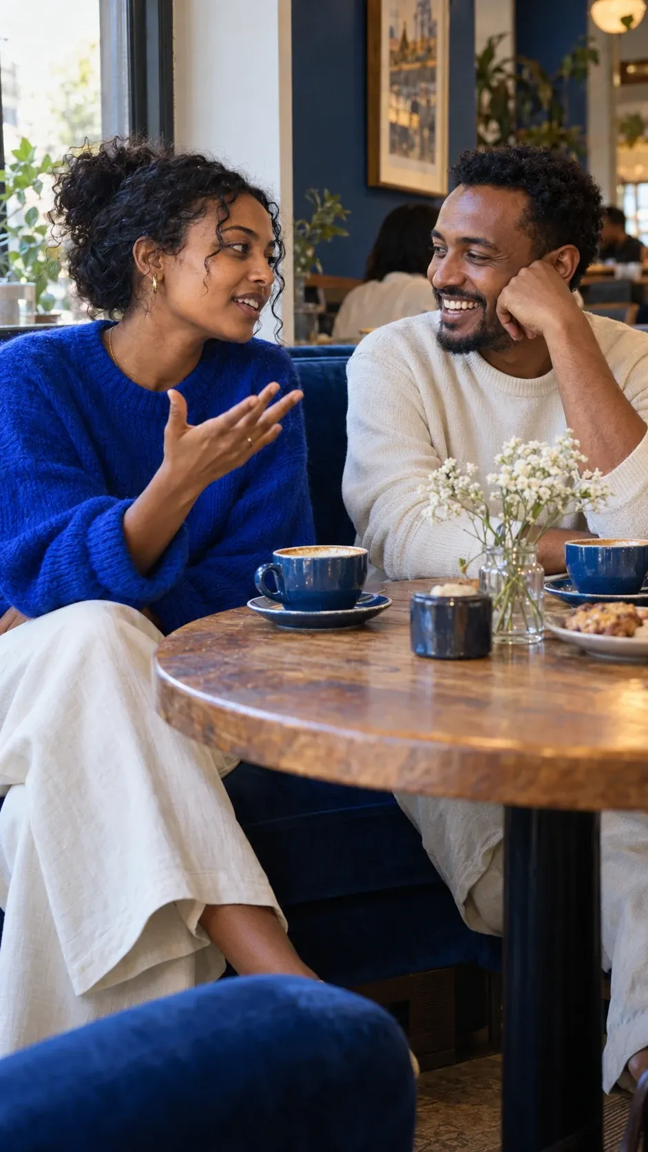 Two adults talking over coffee at a cafe.