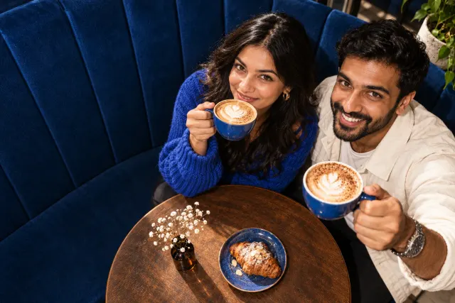 AI-created illustrative photo of two fictional adults at a cafe for Ismaili Talo.