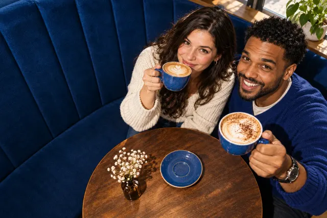 AI-created illustrative photo of two fictional adults at a cafe for Jehovah’s Witness Talo.